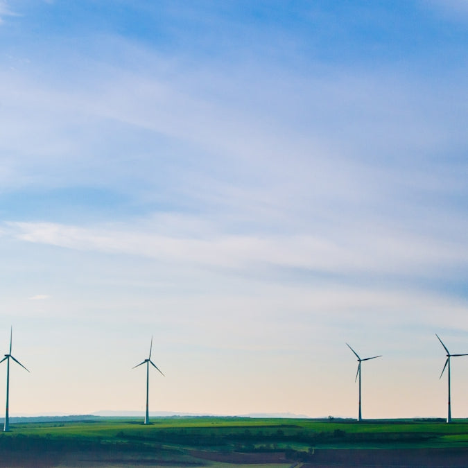 white windmills on green grass field under white clouds and blue sky