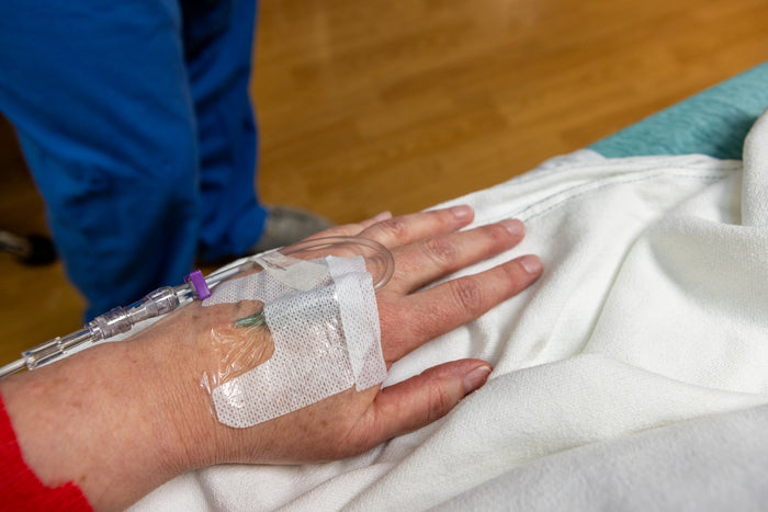 An iv drip is in a patient's hand.
