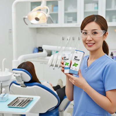 A dental hygienist holding up a tube of Mi Paste Oral Paste